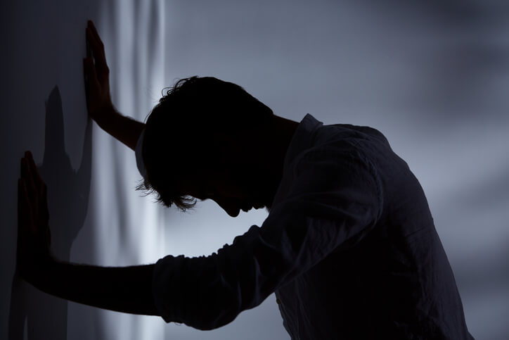Man in shadows leaning against wall Man in shadows leaning against wall