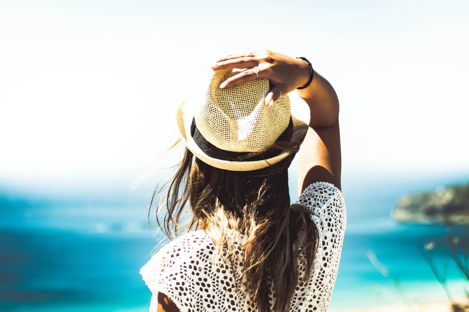 woman with hat looking at blue water woman with hat looking at blue water