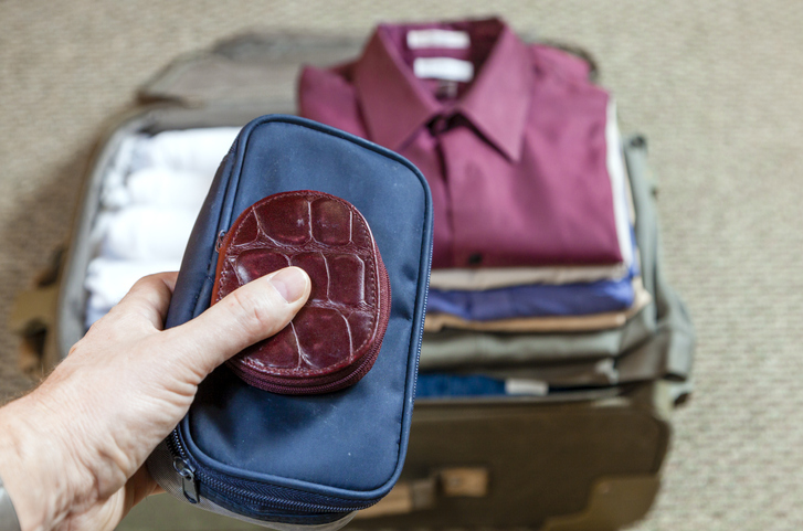 Purse being added to packed suitcase of clothes Purse being added to packed suitcase of clothes