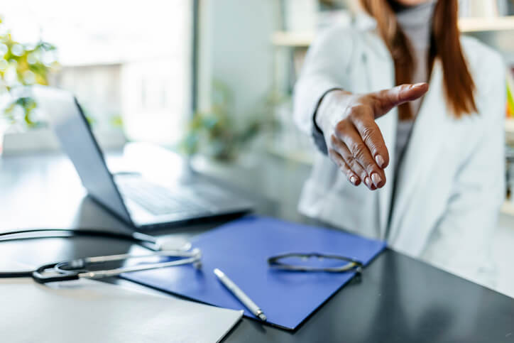 female medicine doctor offering hand to shake in office closeup female medicine doctor offering hand to shake in office closeup