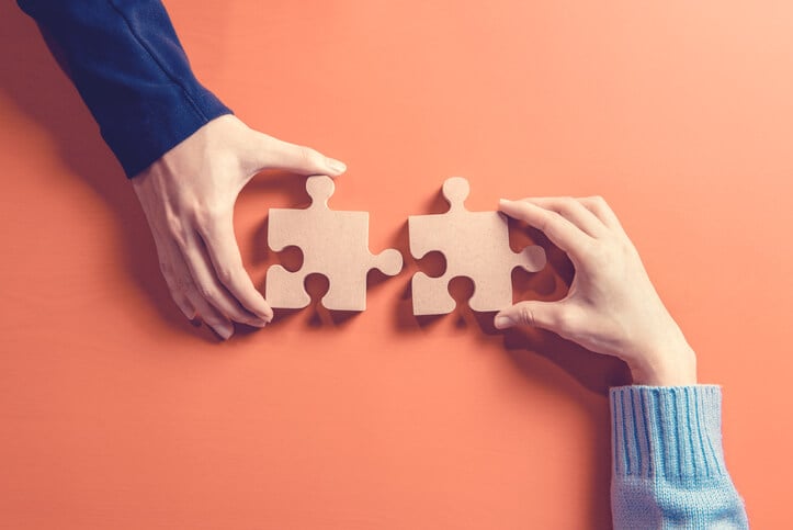 Two different hands fitting together puzzle pieces Two different hands fitting together puzzle pieces
