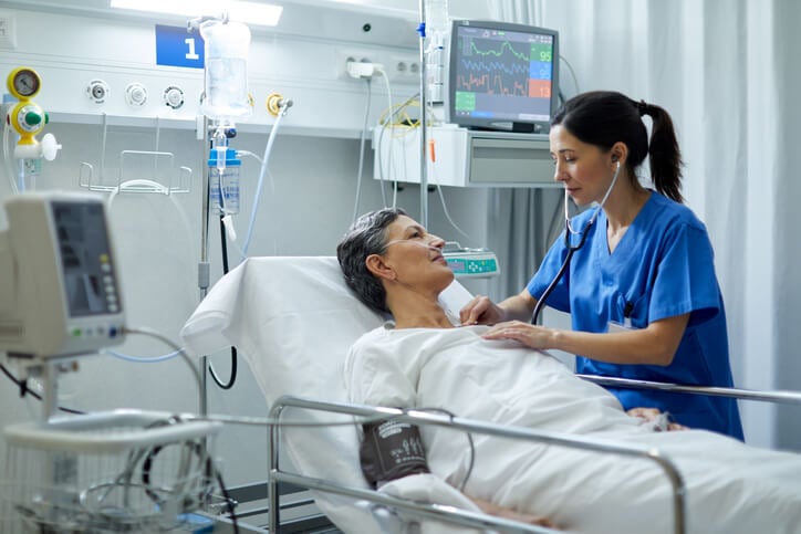 Nurse checking patient's heart with stethoscope Nurse checking patient's heart with stethoscope