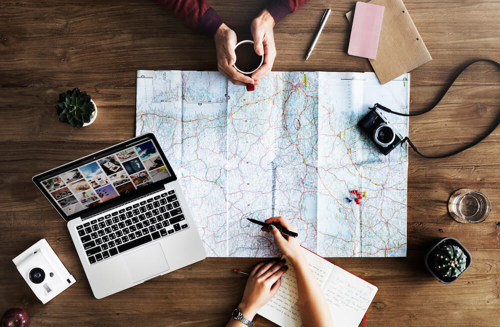 couple's hands with laptop and map spread out couple's hands with laptop and map spread out