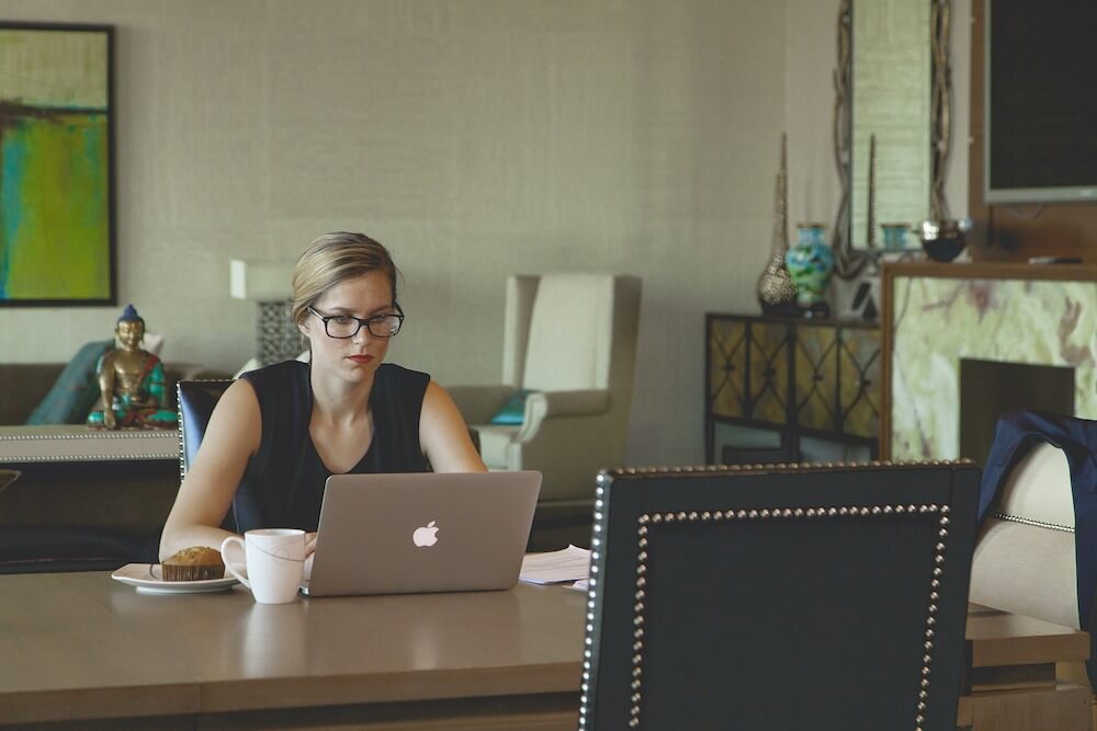 woman working on laptop with coffee and muffin woman working on laptop with coffee and muffin