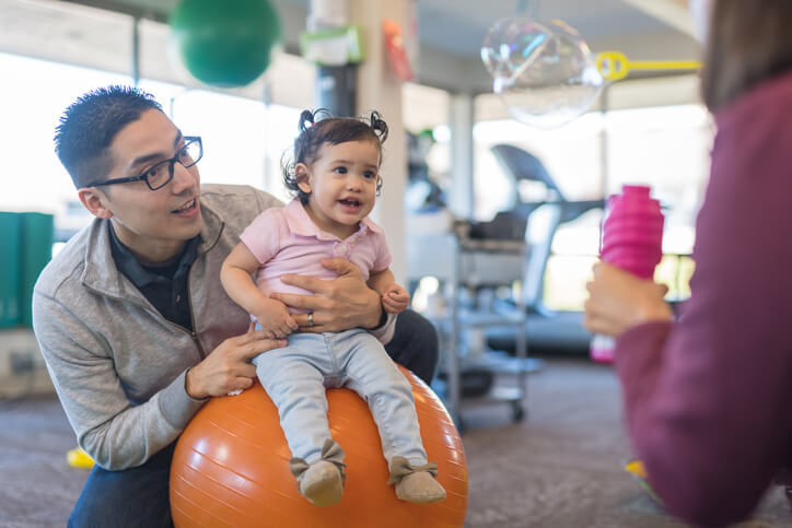 therapist blowing bubbles for child on yoga ball therapist blowing bubbles for child on yoga ball