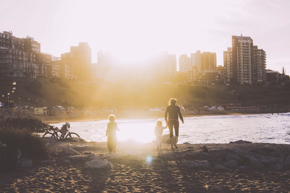 Parent with children on beach near city Parent with children on beach near city