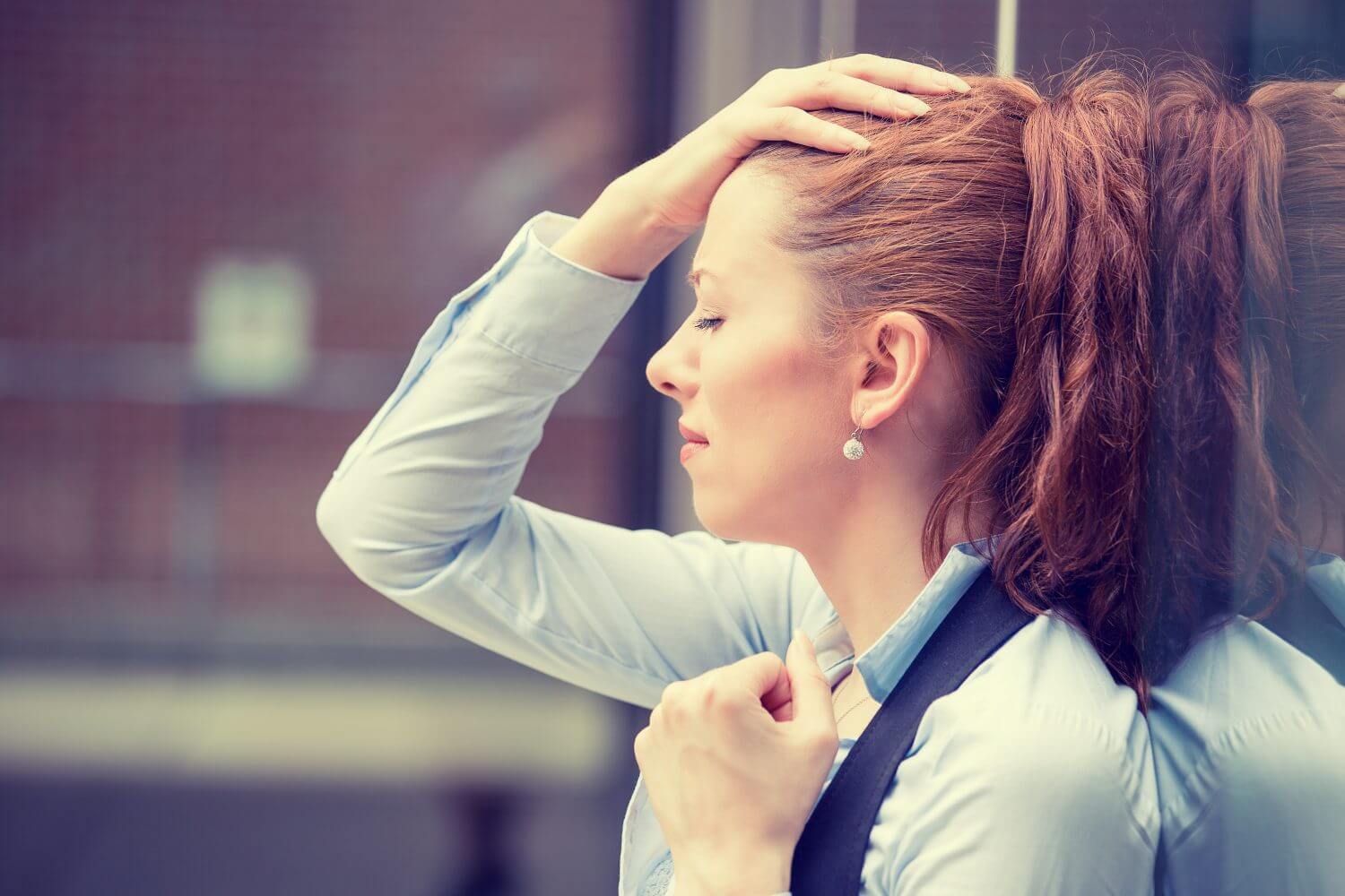 Woman with hand on forehead looking distressed Woman with hand on forehead looking distressed