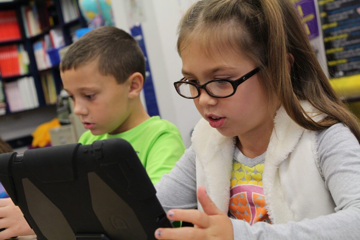 2 children with one looking at tablet 2 children with one looking at tablet