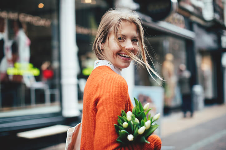 Smiling woman holding tulips looking over shoulder Smiling woman holding tulips looking over shoulder