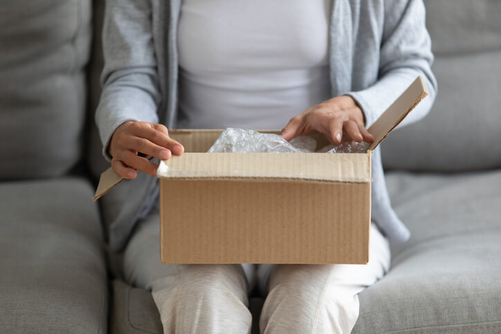 Woman opening mail package on her lap Woman opening mail package on her lap