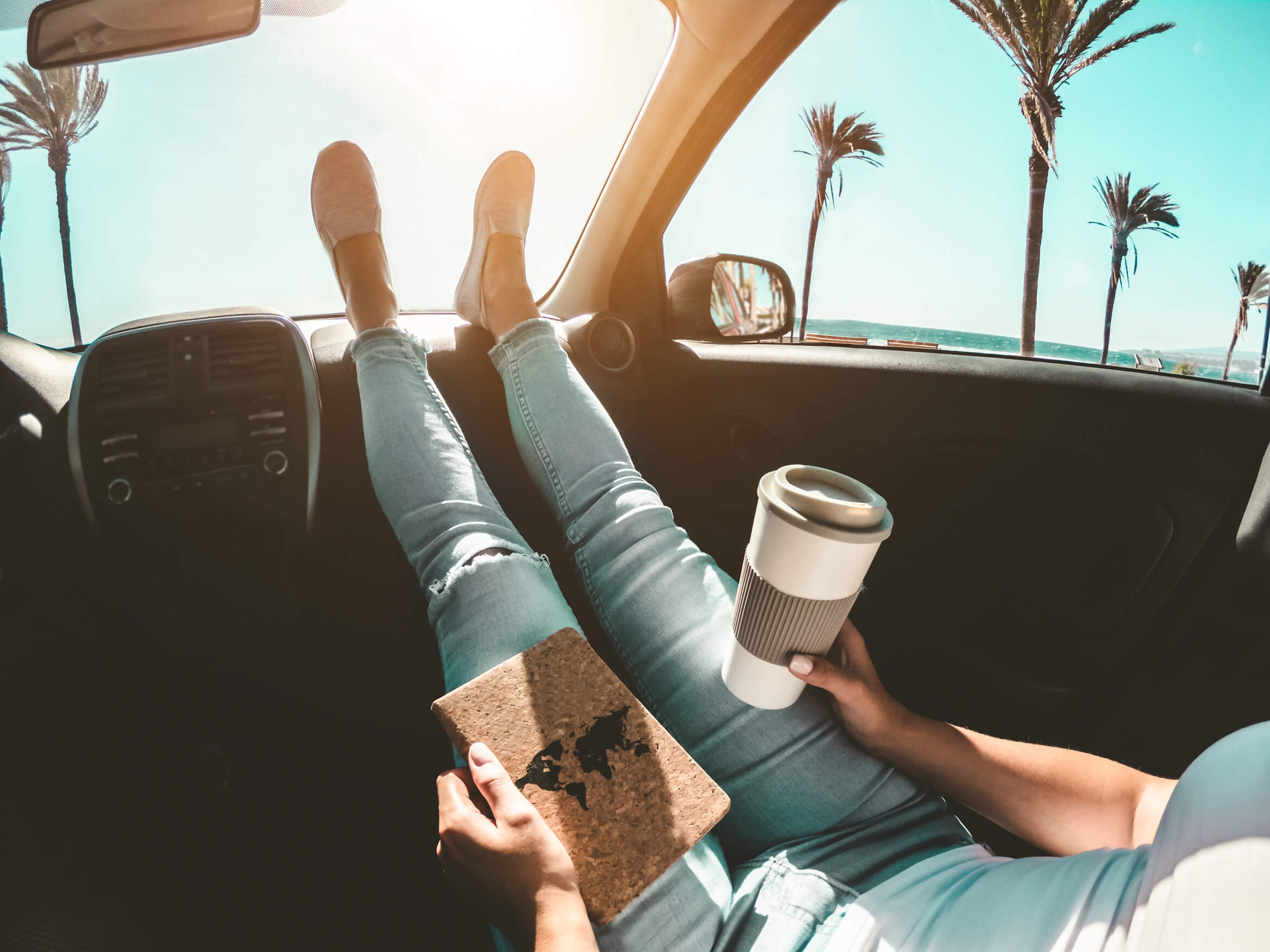 woman relaxing in a car with coffee and palm trees outside woman relaxing in a car with coffee and palm trees outside