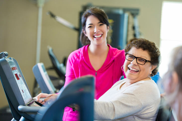 trainer helping senior woman with exercise machine trainer helping senior woman with exercise machine