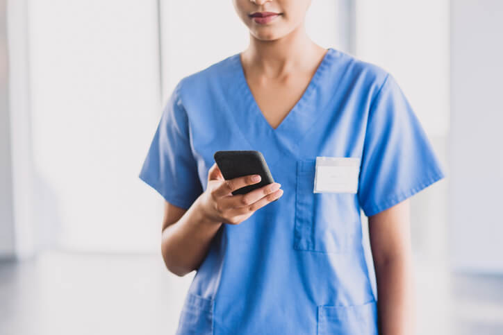 Woman in scrubs looking at cellphone Woman in scrubs looking at cellphone
