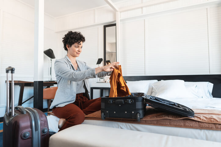 Woman folding clothes into suitcase Woman folding clothes into suitcase