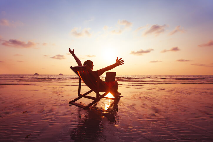Person working on laptop on chair in ocean shallows Person working on laptop on chair in ocean shallows