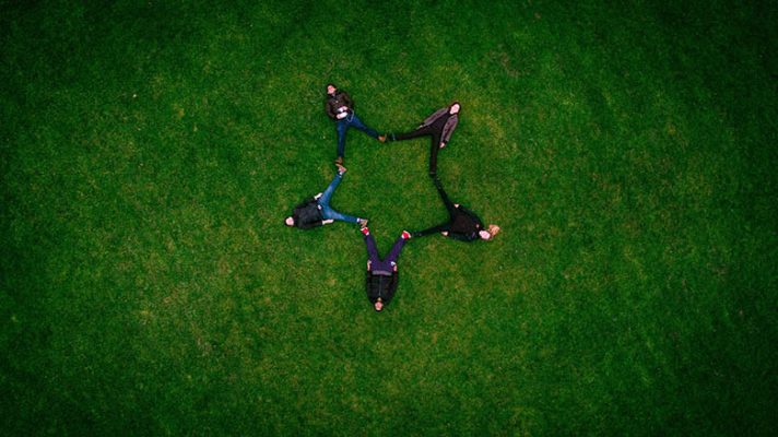 group of people standing in grass with hands connected, seen from above group of people standing in grass with hands connected, seen from above