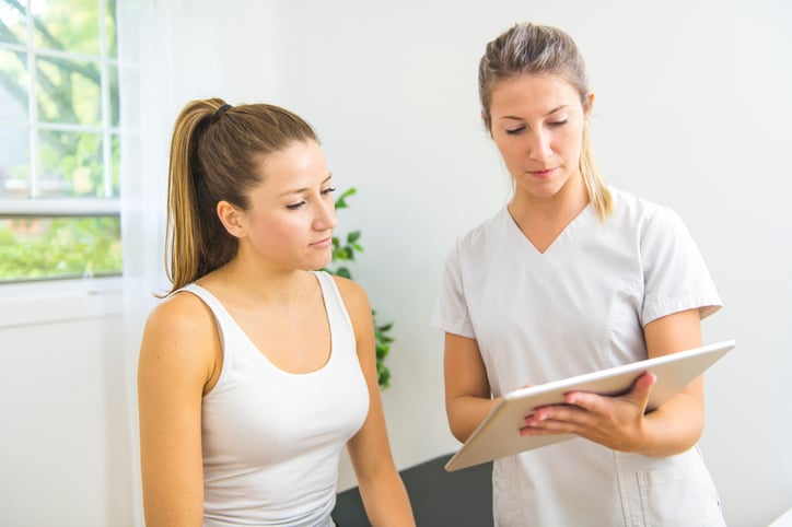 Physical therapist using a tablet with a patient Physical therapist using a tablet with a patient