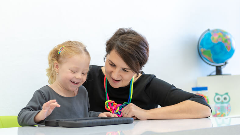 Occupational therapist working with toddler on device Occupational therapist working with toddler on device