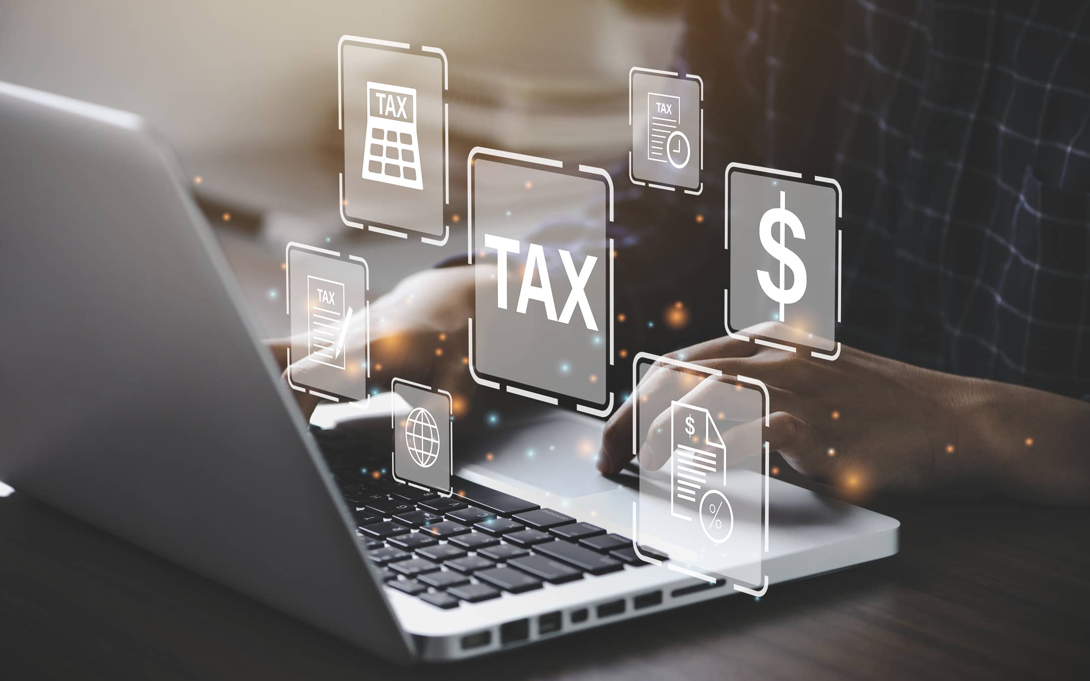hands type on laptop keyboard as text bubbles like taxes and money float around the screen hands type on laptop keyboard as text bubbles like taxes and money float around the screen