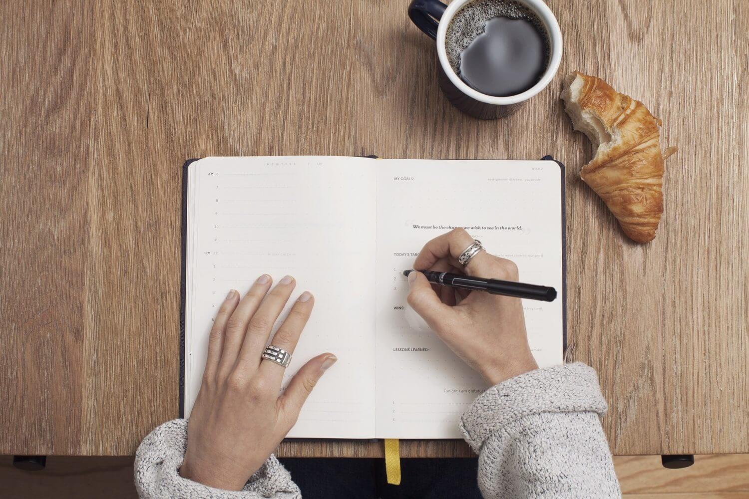 Looking down on woman with pen writing in journal Looking down on woman with pen writing in journal