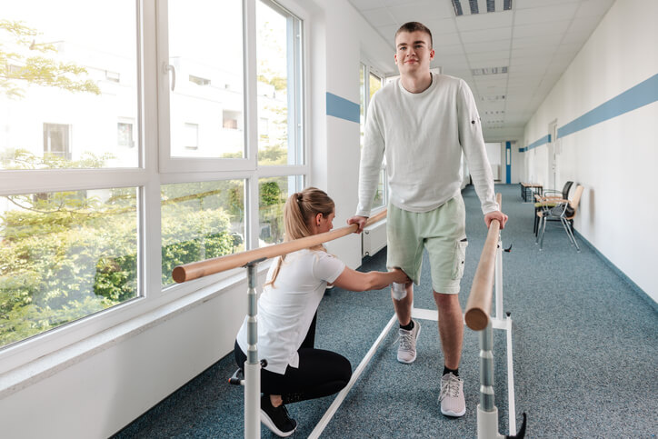 Woman touching young man's knee during sports rehabilitation Woman touching young man's knee during sports rehabilitation
