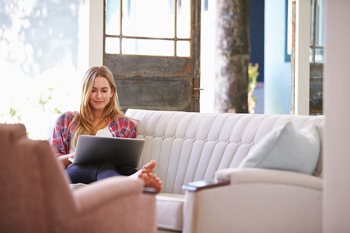 woman comfortable on couch with laptop woman comfortable on couch with laptop