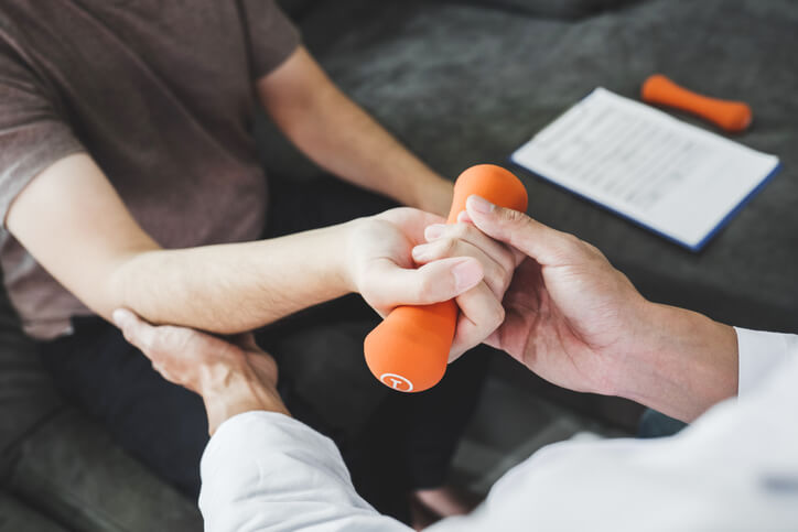 Physical therapy helping patient with a hand weight Physical therapy helping patient with a hand weight