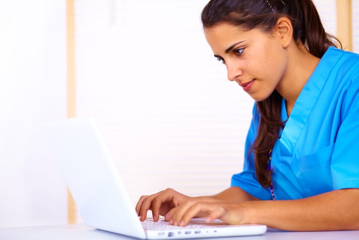 Nurse looking closely at laptop screen Nurse looking closely at laptop screen