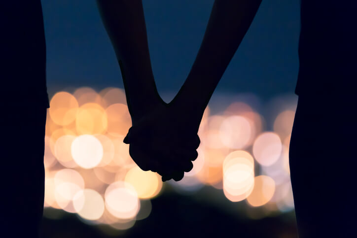 couple holding hands against city lights couple holding hands against city lights