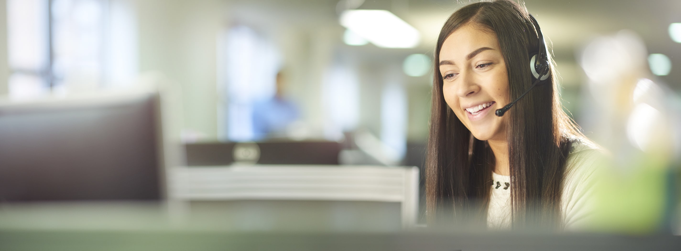 brunetter customer service rep smiles and chats on headphone